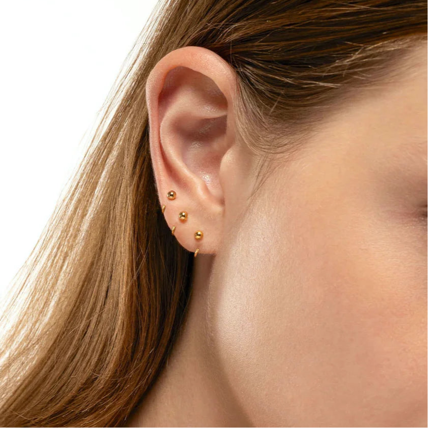 Side profile of model wearing sterling silver ball hoop earrings — poke-free, lightweight design for all-day comfort.