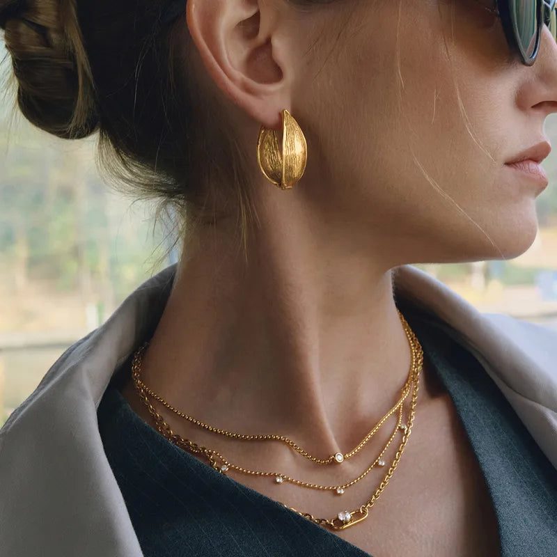 Close-up of Liva gold hoop earrings — chunky 18k gold-plated hoops, lightweight and waterproof for daily wear.